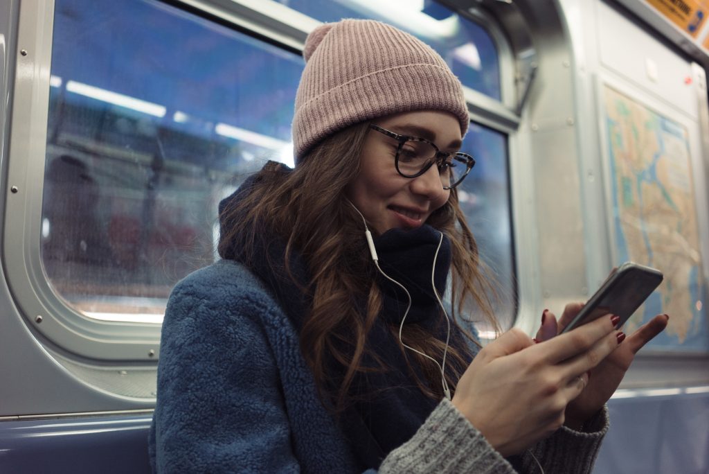 Portrait,Of,A,Smiling,Pretty,Girl,In,Earphones,Using,Mobile